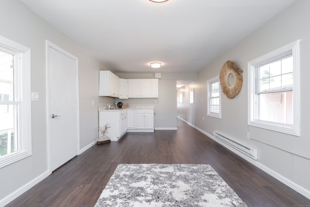 interior space with white cabinets, baseboard heating, sink, and dark hardwood / wood-style flooring