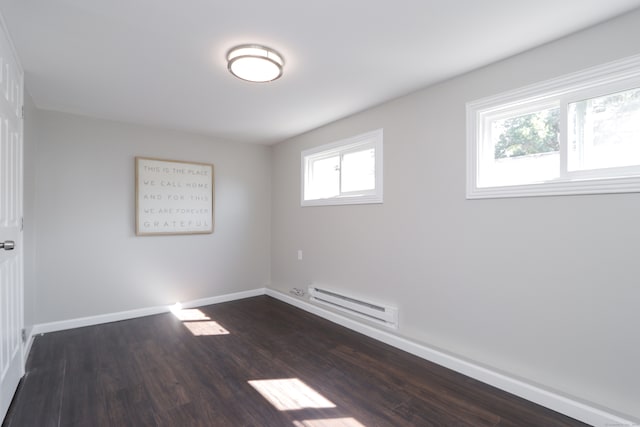 unfurnished room with a baseboard heating unit and dark wood-type flooring