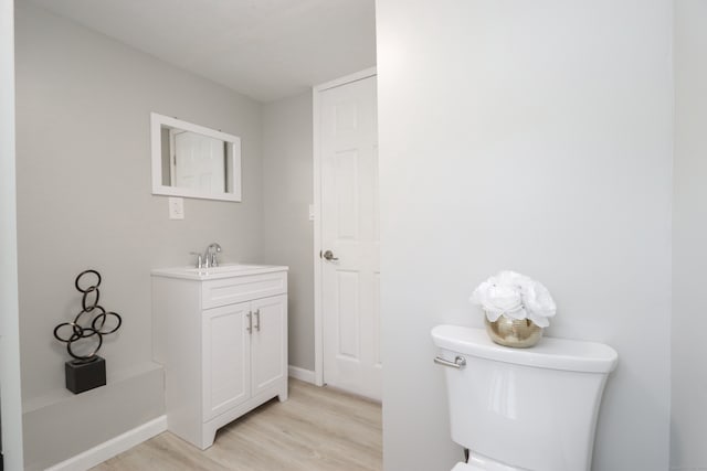 bathroom with wood-type flooring, vanity, and toilet