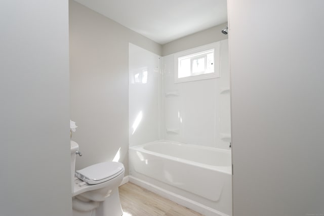 bathroom with shower / bathtub combination, toilet, and wood-type flooring