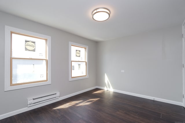 unfurnished room featuring baseboard heating and dark hardwood / wood-style flooring