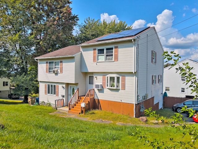 view of front of property with cooling unit, solar panels, and a front yard