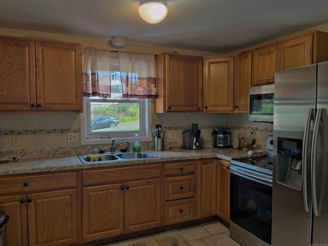 kitchen featuring light tile patterned floors, sink, a textured ceiling, appliances with stainless steel finishes, and decorative backsplash