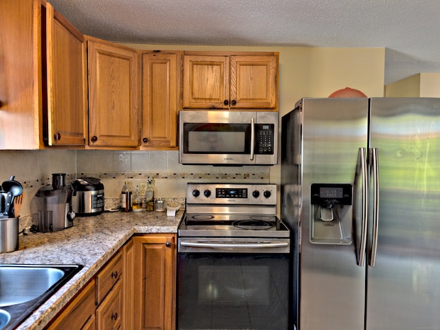 kitchen featuring light stone countertops, a textured ceiling, stainless steel appliances, and backsplash