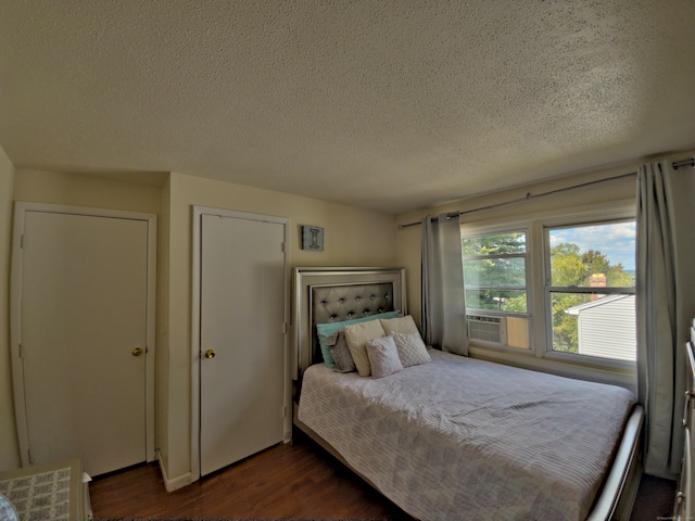 bedroom with cooling unit, a textured ceiling, and dark hardwood / wood-style floors