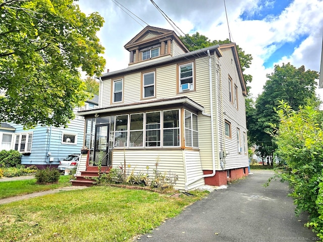 view of front of house with a front yard and a sunroom