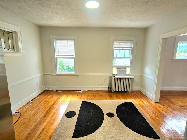 unfurnished room featuring light hardwood / wood-style flooring, plenty of natural light, and radiator heating unit