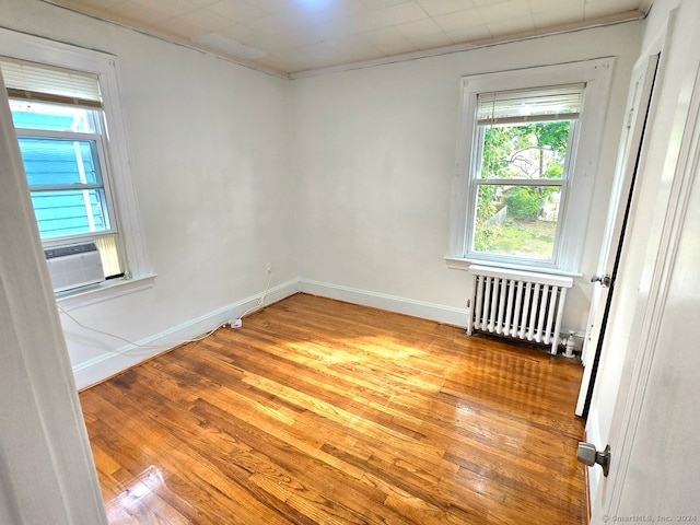 spare room featuring radiator heating unit, cooling unit, light hardwood / wood-style floors, and crown molding