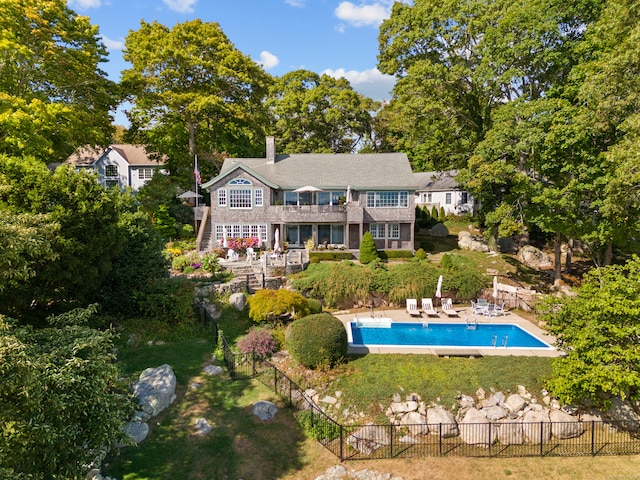 back of house with a balcony, a yard, a fenced in pool, and a patio area