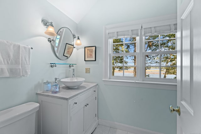 bathroom with tile patterned floors, lofted ceiling, vanity, and toilet