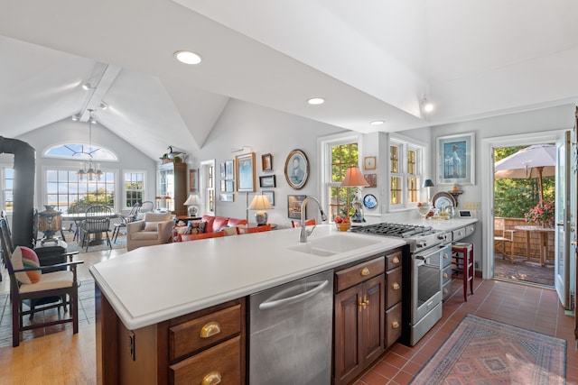 kitchen featuring vaulted ceiling with beams, an island with sink, sink, a chandelier, and appliances with stainless steel finishes