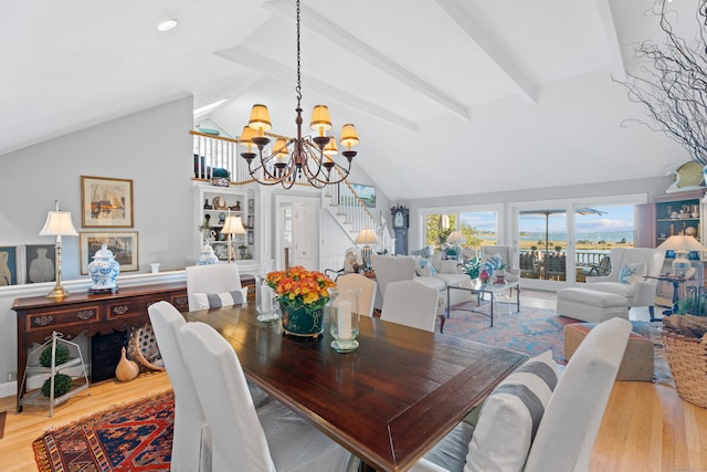 dining space with wood-type flooring, an inviting chandelier, beamed ceiling, and high vaulted ceiling