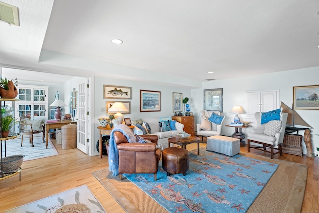 living room featuring french doors, light hardwood / wood-style floors, and a wealth of natural light