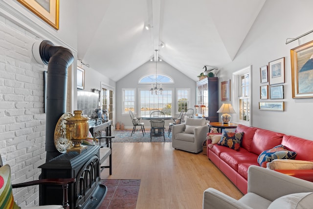 living room with brick wall, vaulted ceiling with beams, hardwood / wood-style flooring, and a wood stove