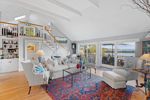 living room featuring a water view, beam ceiling, light hardwood / wood-style flooring, and high vaulted ceiling