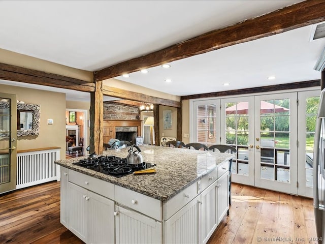 kitchen featuring black gas cooktop, light hardwood / wood-style flooring, a kitchen island, white cabinets, and french doors