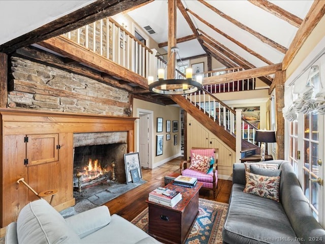 living room with a stone fireplace, beam ceiling, high vaulted ceiling, hardwood / wood-style floors, and an inviting chandelier