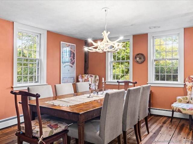 dining space with hardwood / wood-style flooring, plenty of natural light, a baseboard radiator, and a notable chandelier