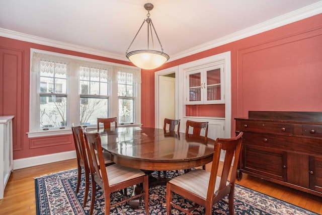 dining room with ornamental molding, light wood-type flooring, and a healthy amount of sunlight