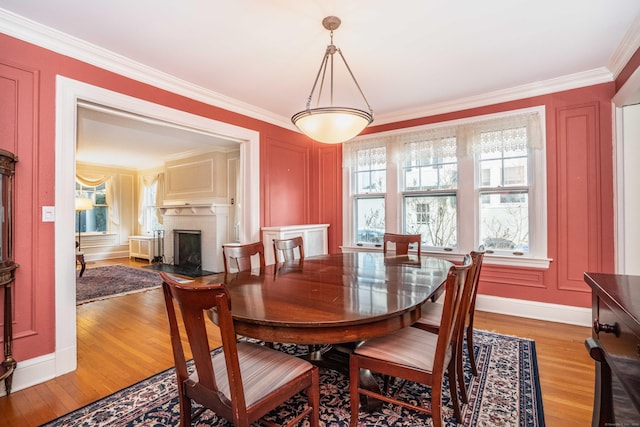 dining space with light hardwood / wood-style floors, crown molding, and a brick fireplace