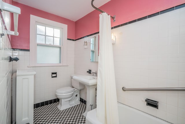 bathroom with toilet, shower / bath combo with shower curtain, and tile walls