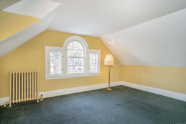 additional living space featuring radiator heating unit, carpet floors, and vaulted ceiling