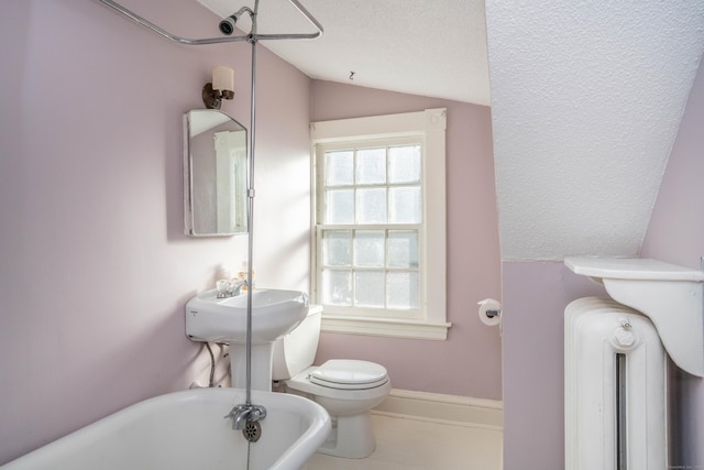 bathroom featuring a textured ceiling, lofted ceiling, toilet, and a bathing tub