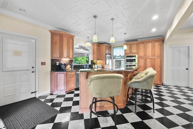 kitchen with pendant lighting, ornamental molding, a kitchen island, appliances with stainless steel finishes, and a breakfast bar