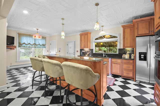 kitchen featuring stainless steel fridge, ornamental molding, a kitchen island, a baseboard heating unit, and a kitchen breakfast bar