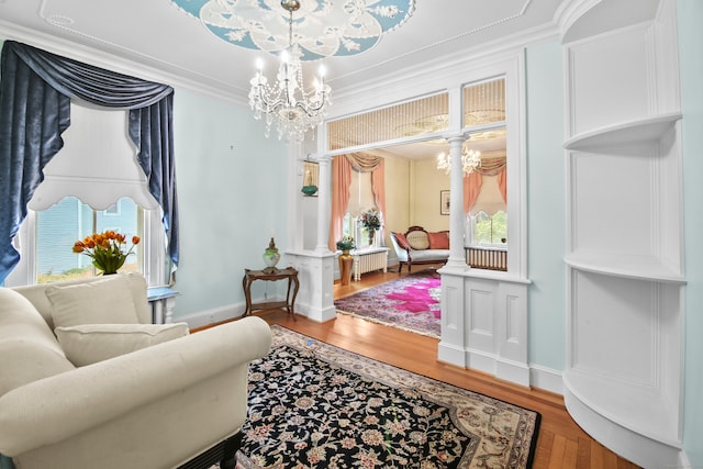 sitting room with ornamental molding, radiator, hardwood / wood-style floors, and an inviting chandelier