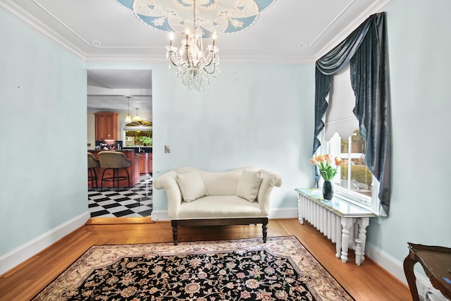 living area featuring light hardwood / wood-style flooring, radiator, an inviting chandelier, and crown molding