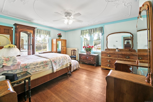 bedroom featuring ceiling fan, ornamental molding, dark wood-type flooring, and multiple windows