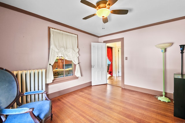 living area with radiator heating unit, ornamental molding, light hardwood / wood-style floors, and ceiling fan