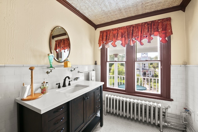 bathroom with radiator, vanity, tile walls, and crown molding