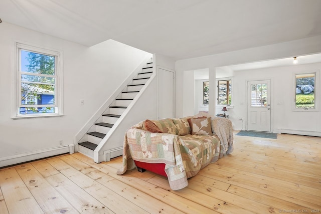 living room featuring a baseboard heating unit, light hardwood / wood-style flooring, and a healthy amount of sunlight