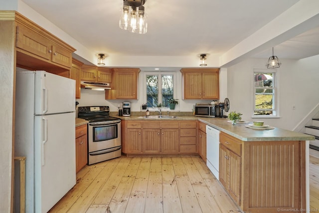 kitchen with hanging light fixtures, light wood-type flooring, sink, kitchen peninsula, and stainless steel appliances