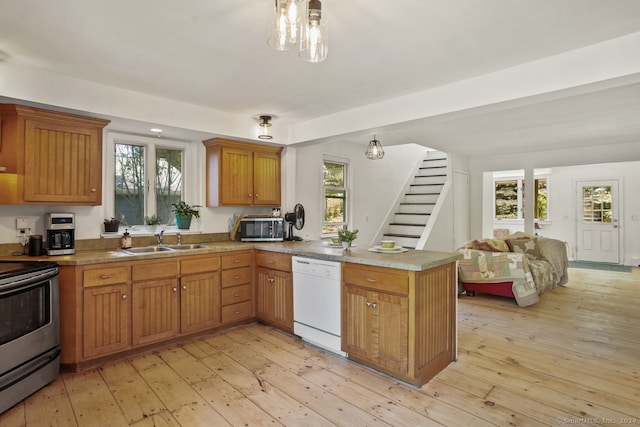 kitchen with kitchen peninsula, white dishwasher, sink, stainless steel range with electric stovetop, and light hardwood / wood-style floors