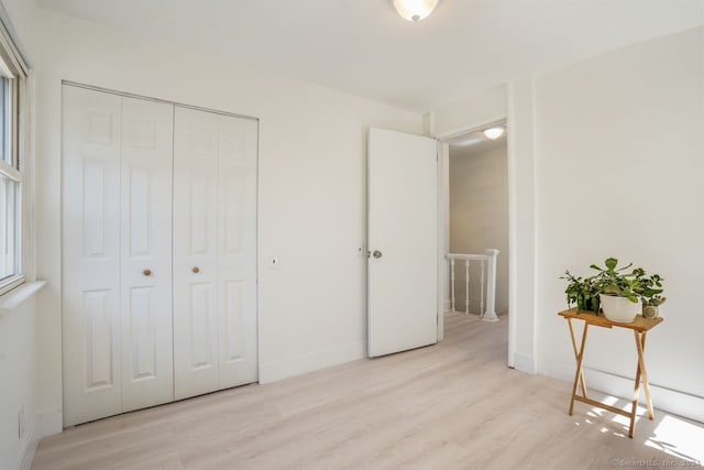 unfurnished bedroom featuring light hardwood / wood-style flooring and a closet