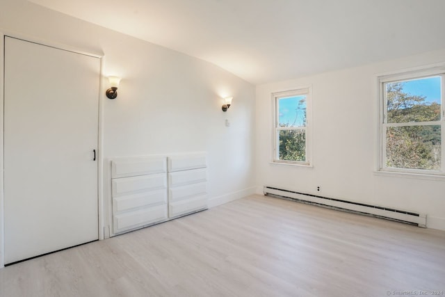 unfurnished bedroom featuring a baseboard radiator, vaulted ceiling, and light wood-type flooring