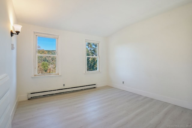 empty room featuring light hardwood / wood-style floors, a baseboard radiator, and lofted ceiling