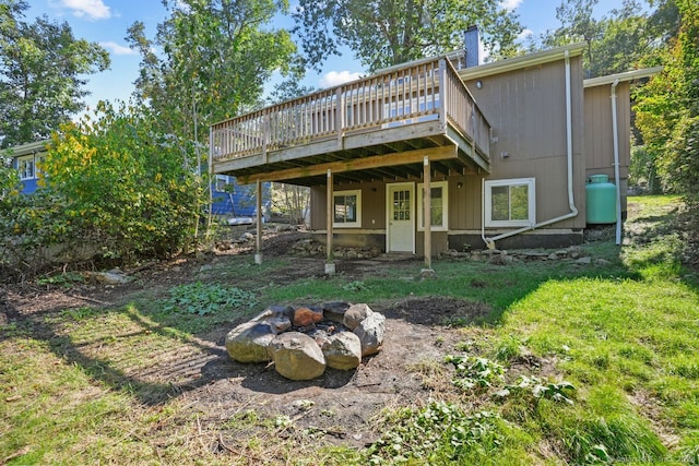 rear view of house featuring a deck, a fire pit, and a lawn