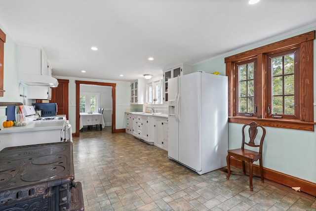 kitchen featuring white fridge with ice dispenser, white cabinets, and a wealth of natural light