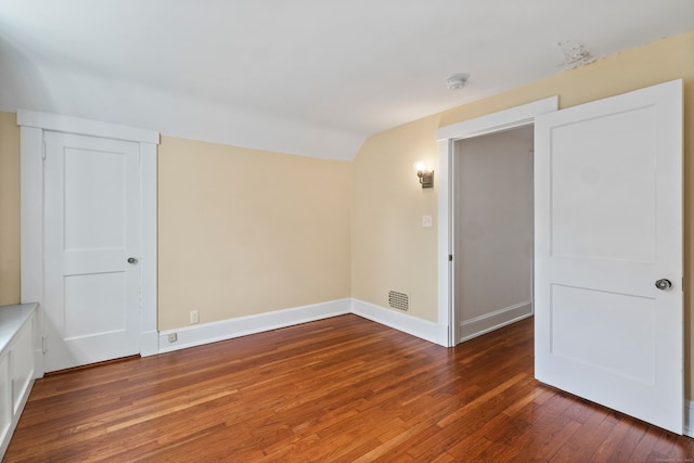 empty room featuring vaulted ceiling and dark wood-type flooring