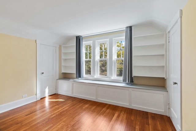 spare room with light wood-type flooring and lofted ceiling