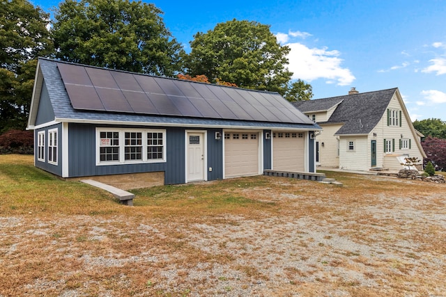 view of front of home with a garage, solar panels, and a front lawn