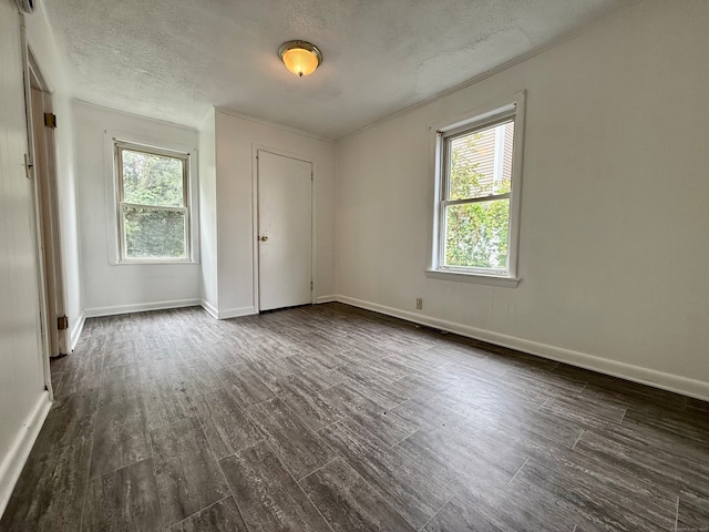 unfurnished room featuring a textured ceiling, a healthy amount of sunlight, and dark wood-type flooring