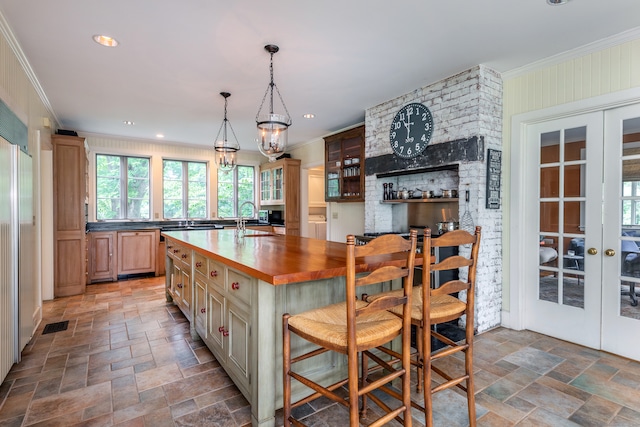 kitchen featuring french doors, an island with sink, and crown molding