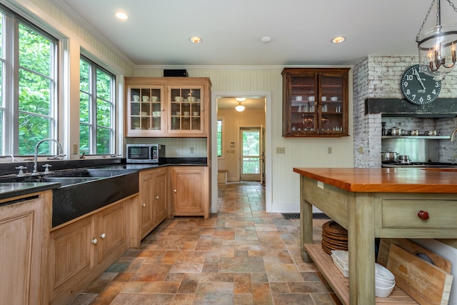 kitchen with ornamental molding, butcher block countertops, a wealth of natural light, and hanging light fixtures