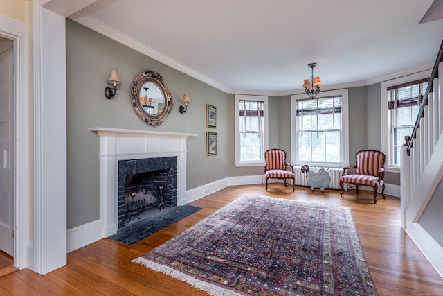 living area featuring wood-type flooring, ornamental molding, and a tiled fireplace