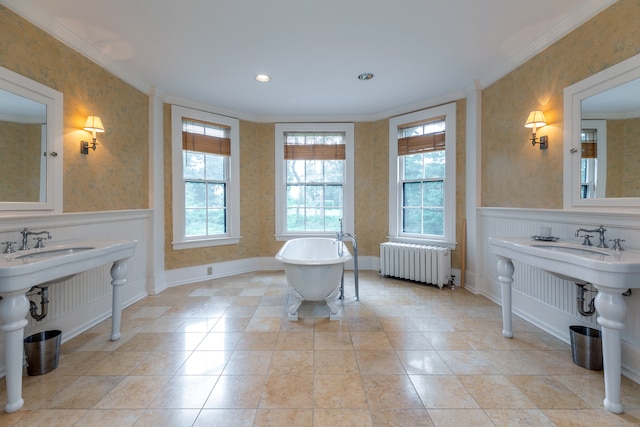 bathroom with double sink, radiator heating unit, crown molding, and a washtub